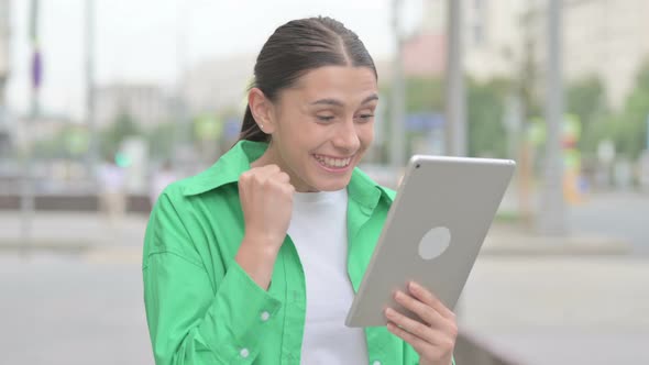 Hispanic Woman Celebrating Success on Tablet Outdoor