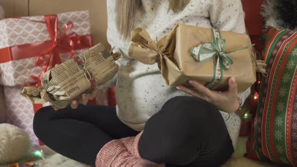 Pregnant Woman Holding Christmas Gifts Under the Christmas Tree