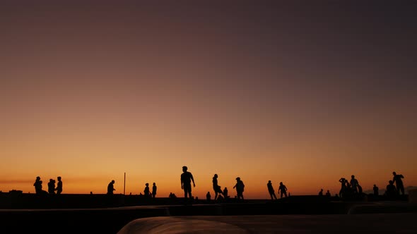 Silhouette of Young Jumping Skateboarder Riding Longboard, Summer Sunset Background. Venice Ocean