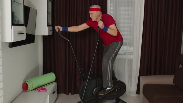 Healthy Elderly Senior Grandfather Model Exercising Sport Workout on Orbitrek in Room at Home