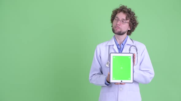 Young Bearded Man Doctor Presenting While Showing Digital Tablet