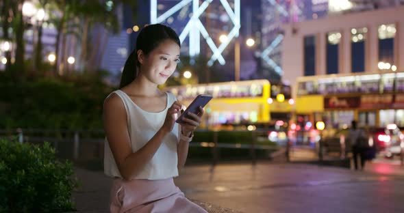 Woman use of mobile phone in city at night