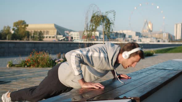 Serious Young Sportsman Doing Pushups Outside in City on Summer Day