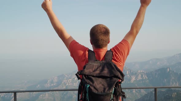 Adventurous Man on Top of the Mountain Raises His Arms in Victory