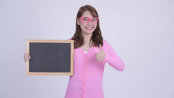 Young Happy Asian Nerd Woman Holding Blackboard and Giving Thumbs Up