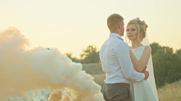 The Wedding Couple Communicates on the Background of the Sky the Bride with a Bouquet of Flowers