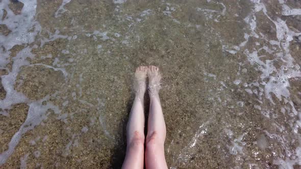 Sea Water Washes Female Legs on a Beach