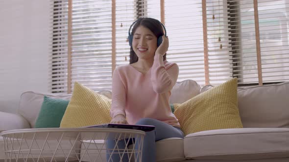 Asian woman uses her smartphone. uses headphones to listen to music