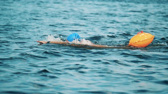 Male Athlete Swimming in a River with a Tow Float