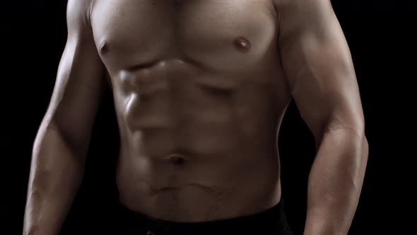 Man Shows a Muscular Strong Body Closeup on a Black Background