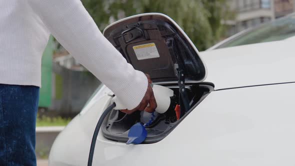 A Young African American Man Connects an Electric Car to the Charger