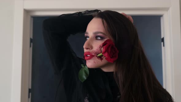 Beauty Portrait of Elegant Sexy Girl with Red Rose in Her Mouth on a Black Background