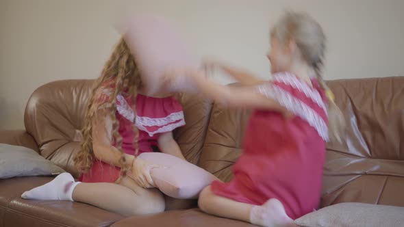 Happy Blond Caucasian Mother and Little Daughter in the Same Dresses Playing at Home, the Girl Hits