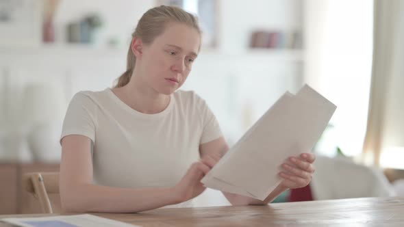 Beautiful Young Woman Reading Documents in Office