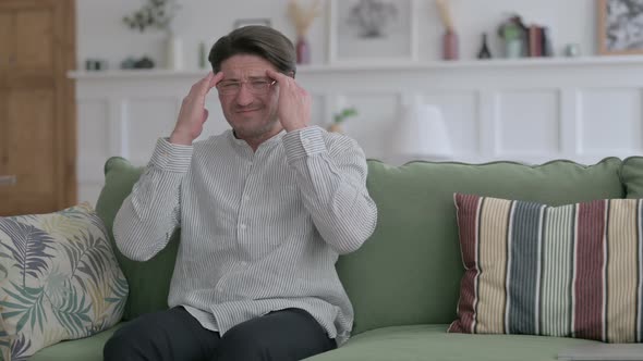 Man having Headache while Sitting on Sofa