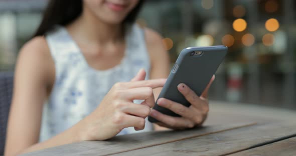 Woman using mobile phone in outdoor coffee shop