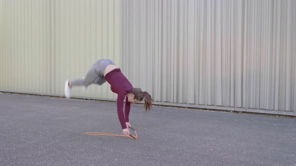 Young woman skipping rope and cartwheeling in the street