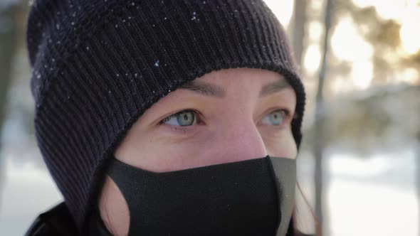 Portrait of a Young Woman in a Black Mask Stands in the City in the Winter