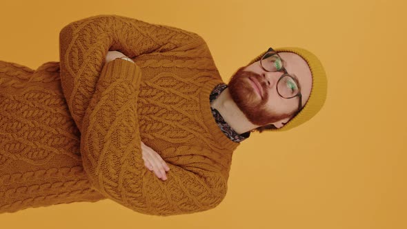 Thoughtful Bearded Hipster in His 30s Wearing the Sweater and Winter Hat Thinking Orange Background