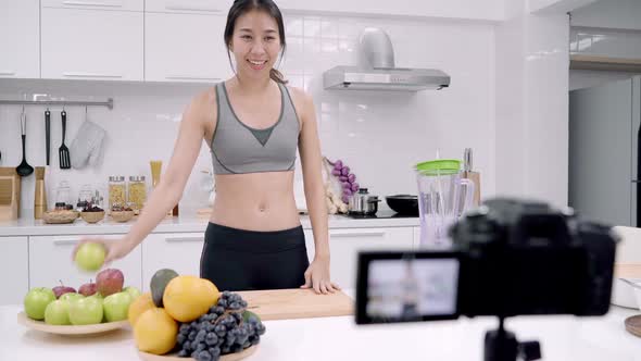 Asian woman using camera recording how to make apple juice video for her subscriber.