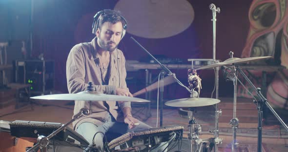 Drummer playing on electronic drum set in a recording studio