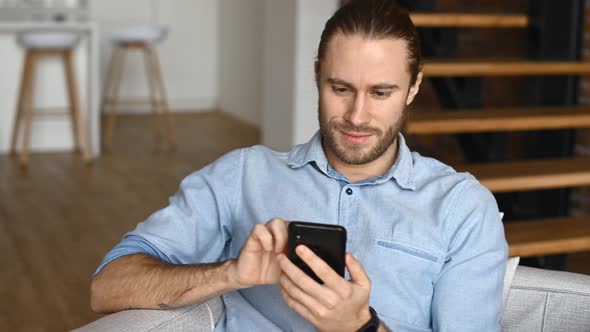 A Hipster Guy is Using a Smartphone Indoor