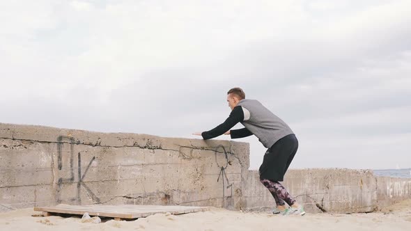 Young Man Doing Parkour Tricks on the Beach Near the Sea