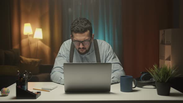 Young Arab Businessman Sitting in Office and Writing in Notes in Notebook Working on Laptop Computer