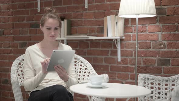 Attractive Young Woman Having Coffee and Using Tablet