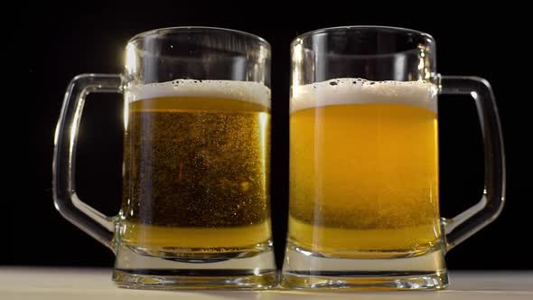 Two Beer Glasses Are Poured with Foamy Golden Light Beer on Black Background, Beer with Friend
