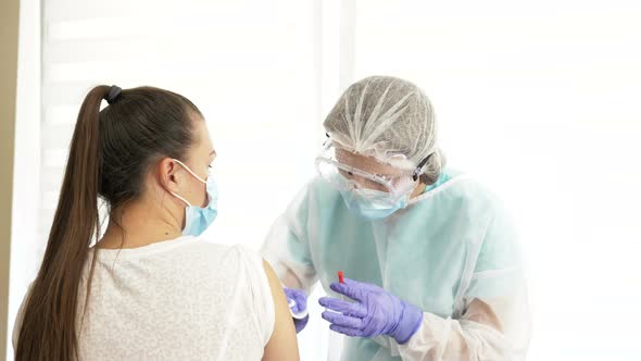 Nurce in protective suit inject vaccine shot to patient.