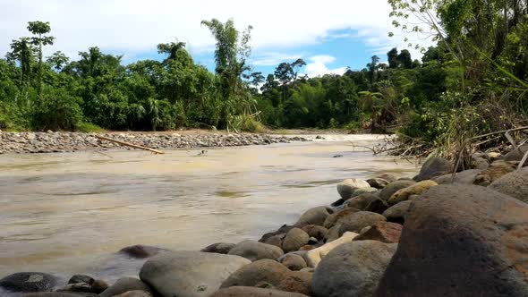 A timelapse of a tropical river with brown colored water in which the river