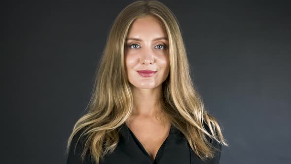 Young blonde woman raises a gold monero coin to show to the camera.