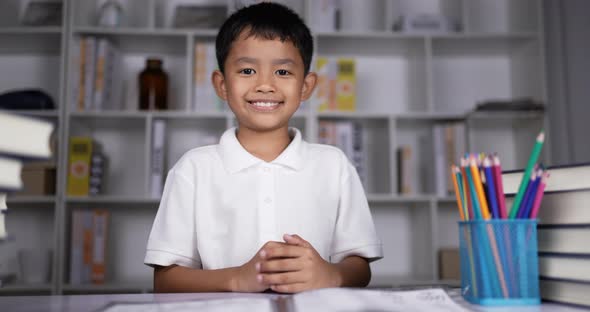 Boy sitting on desk and waving hands gesturing hello or goodbye.