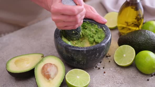 Making Guacamole Sauce  Woman Mashing Avocado in a Marble Mortar with Pestle at Domestic Kitchen