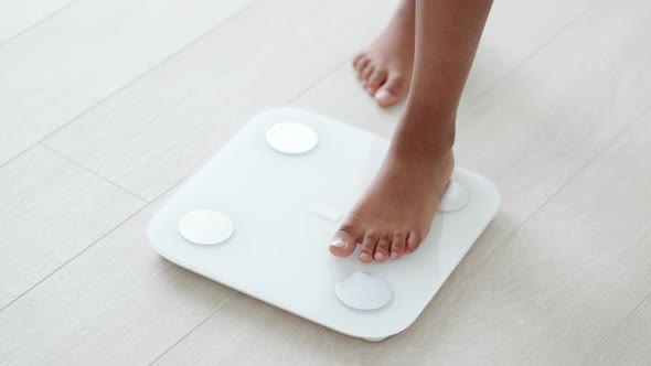 Legs of Black Girl Standing on Scale to Measure Weight