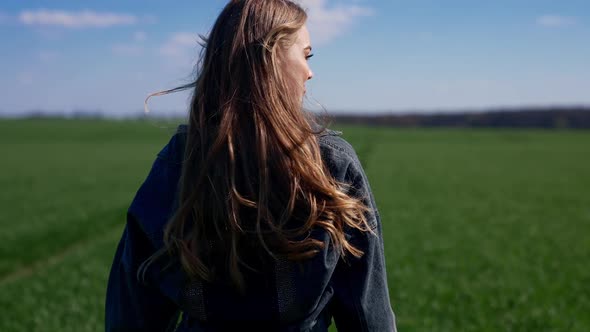 Young girl happily walking in slow motion through field