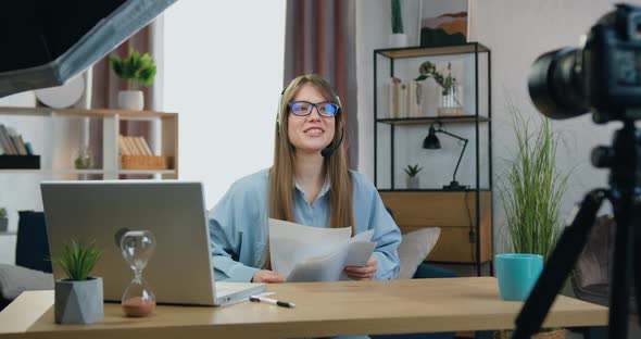 Girl in Wireless Headset Sitting in front of Camera During Online Videomeeting with Spectators