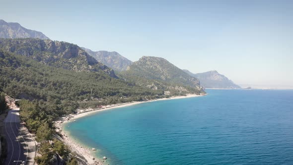 Mountain rocky coastline with green hills and clear sea water surface