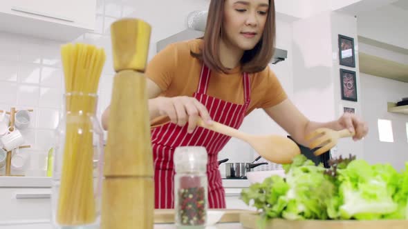Young Asian woman cooking in kitchen at home.