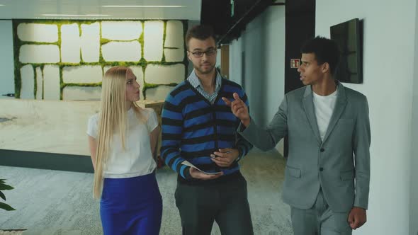 Diverse Colleagues in Office Hall. Man in Suit Walking in Hall of Office with Coworkers Showing