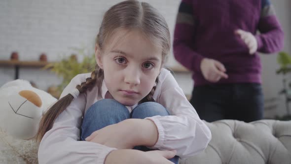 Close-up Face of Beautiful Caucasian Teenage Daughter Hugging Knees and Looking at Camera
