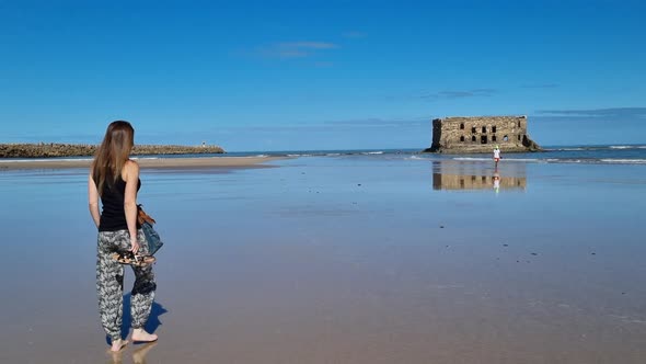 Girl with long hair walks towards the beach in Casa del mar, Tarfaya,, Marroco. Elegant beautiful gi