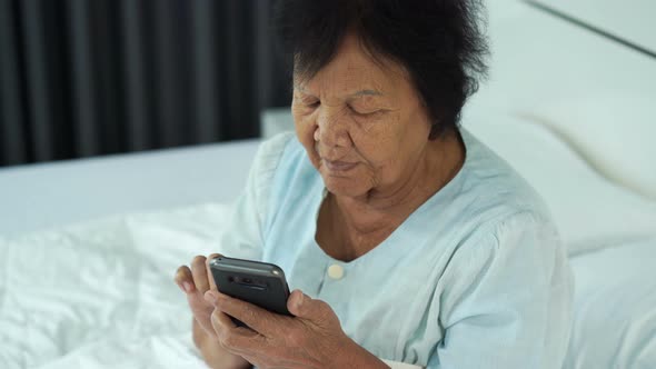 senior woman using mobile phone on a bed