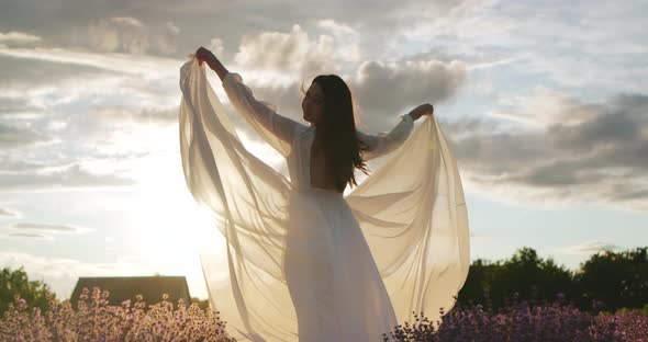 Gentle Girl in a White Light Dress in a Field at Sunset