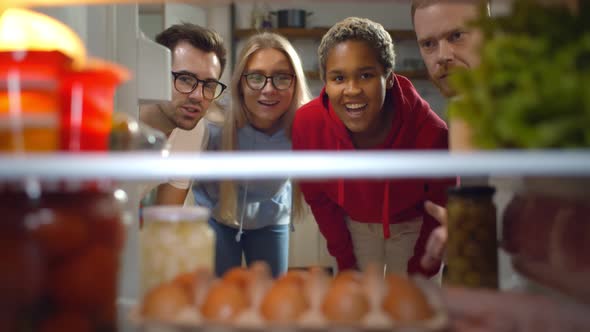 Multiethnic Friends Opening Fridge and Taking Ingredients Cooking Dinner Together in Kitchen