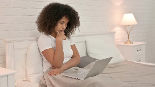 Young African Woman with Laptop Thinking in Bed