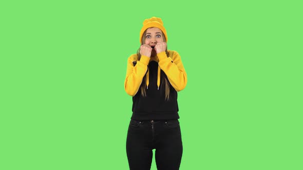 Modern Girl in Yellow Hat Examines Something Then Very Scared and Screaming. Green Screen