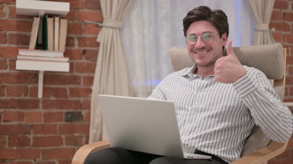 Middle Aged Man with Laptop showing Thumbs Up on Sofa