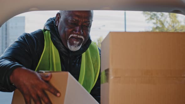 Closeup Happy Mature African American Man in Workwear Uniform Stacking Cardboard Boxes Courier